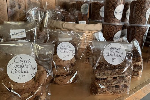 A display of baked goods in clear packaging, including chocolate chip cookies and caramel pecan shortbread.