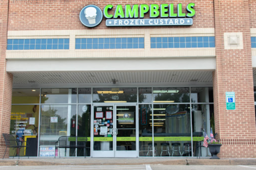 Exterior of Campbells Frozen Custard shop, featuring a large sign and glass entrance with seating visible inside.
