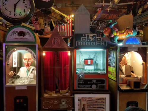 A collection of vintage arcade machines with colorful displays and various themes in a lively setting.