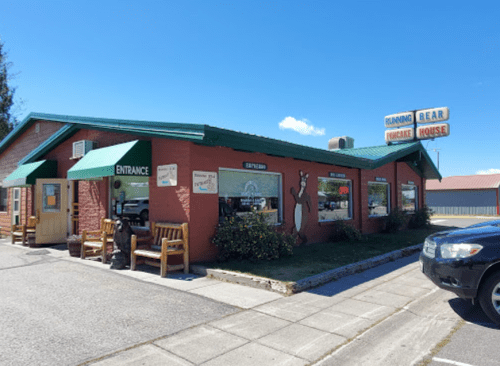 A cozy restaurant with a green roof and bear-themed decor, featuring outdoor seating and a welcoming entrance.