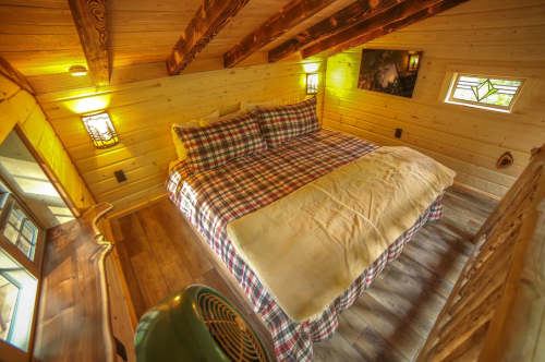 Cozy wooden bedroom with a plaid bedspread, warm lighting, and rustic decor.