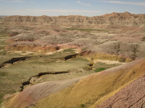 Vast, colorful badlands with rolling hills and valleys under a clear blue sky.