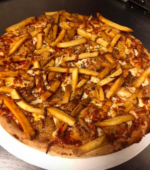 A pizza topped with cheese, sauce, and a generous layer of French fries.