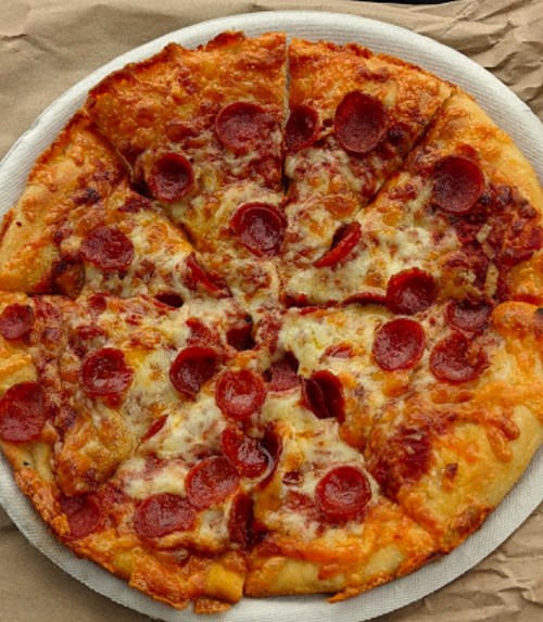 A round pizza topped with melted cheese and pepperoni slices, cut into eight equal slices on a paper plate.