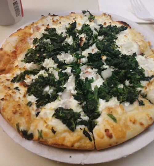 A pizza topped with white cheese and a generous layer of fresh green spinach on a golden crust.