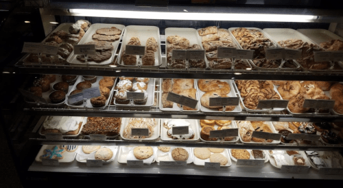 A display case filled with various baked goods, including cookies, pastries, and cakes, all neatly arranged.