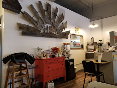 Cozy café interior featuring a red dresser, wooden decor, and a small dining area with chairs and a counter.