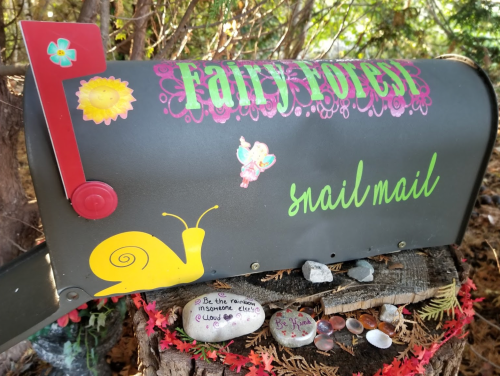 A whimsical mailbox decorated with flowers, a snail, and colorful text reading "Fairy Forest" and "snail mail."