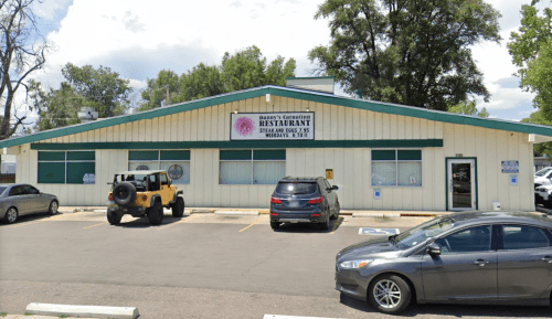 Exterior of a restaurant with a sign reading "Donny's Carnation," featuring parked cars and a clear blue sky.