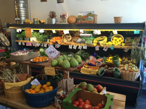 A vibrant display of fresh fruits and vegetables in a market, with colorful baskets and price tags visible.