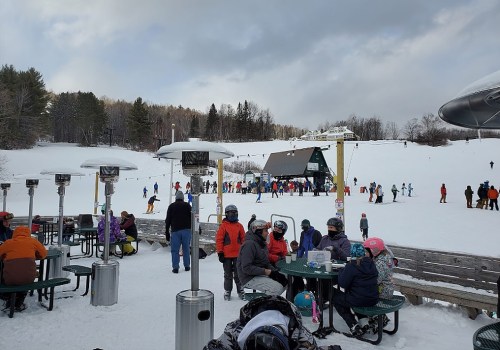 A snowy ski resort scene with people skiing, dining outdoors, and enjoying the winter atmosphere.