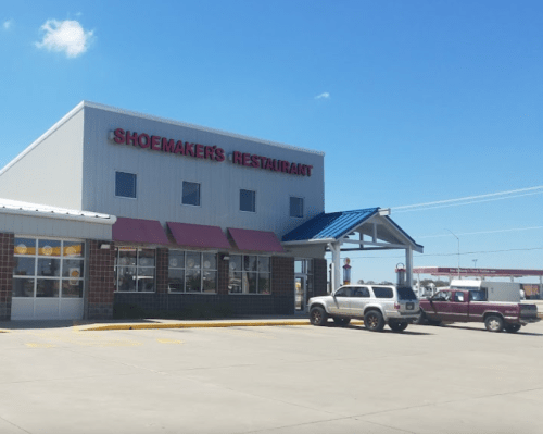 Exterior of Shoemaker's Restaurant with a blue roof and parked vehicles under a clear blue sky.