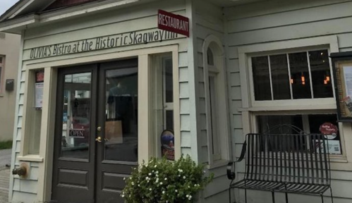 Exterior of Olivia's Bistro, a small, charming restaurant with a sign and open door, surrounded by greenery.