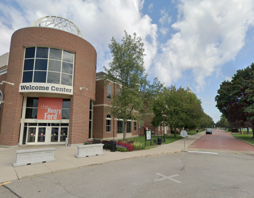 Exterior view of the Henry Ford Welcome Center, featuring brick architecture and landscaped greenery under a cloudy sky.