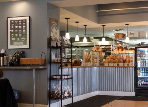 A cozy café interior featuring a display of baked goods, coffee equipment, and a welcoming atmosphere.