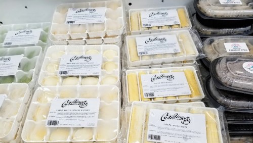 Various packaged desserts displayed in a refrigerated case, labeled with brand names and flavors.