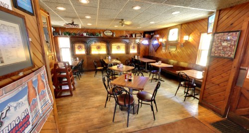 Cozy restaurant interior with wooden walls, tables, and vintage decor, featuring booths and soft lighting.