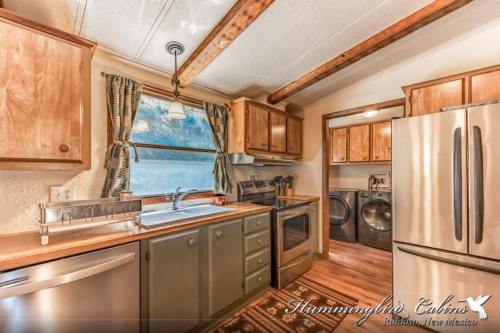 Cozy kitchen with wooden beams, modern appliances, and a laundry area, featuring warm tones and natural light.