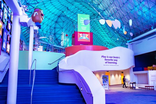Colorful interior of a playful learning space with stairs, bright decor, and a large sign about toys.