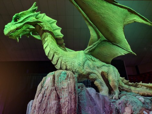 A green dragon sculpture perched on a rocky base, with large wings and intricate details.