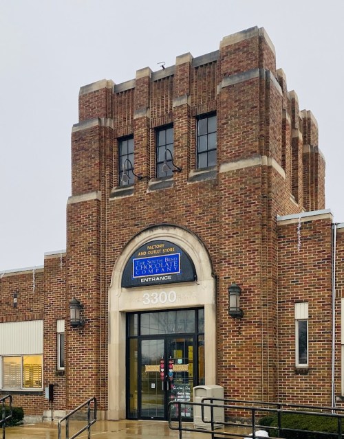 Brick building with a decorative entrance, featuring a sign that reads "Factory and Outlet Store" above the door.