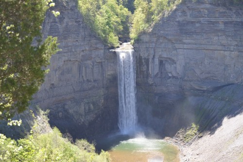 A stunning waterfall cascading into a serene pool, surrounded by lush greenery and rocky cliffs.