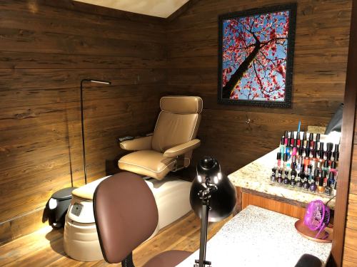 A cozy nail salon with wooden walls, a comfortable chair, and a display of colorful nail polish.