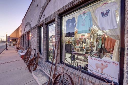 A storefront with a display of clothing and accessories, featuring a sign for "The Pretentious Pig."