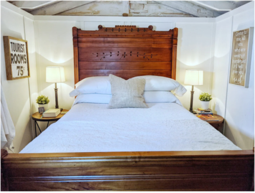 Cozy bedroom with a wooden headboard, white bedding, bedside lamps, and decorative plants on nightstands.
