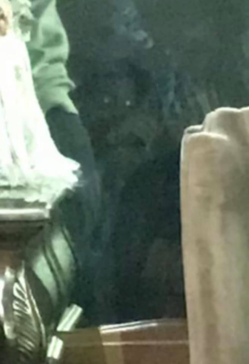 A dimly lit room with a person partially obscured in the background, creating a mysterious atmosphere.