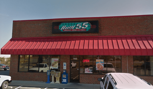 Exterior of Hwy 55 restaurant featuring a red awning, brick facade, and an "Open" sign. Parking lot visible in front.