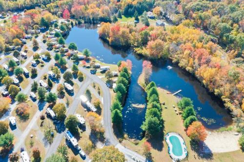 Aerial view of a colorful autumn landscape with a pond, surrounded by trees and a campground with RVs.