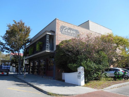 A brick building with a sign reading "Carson Restaurant," surrounded by trees and parked cars.