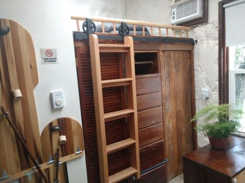A wooden wardrobe with a sliding door, a ladder, and a small air conditioning unit in a cozy room.