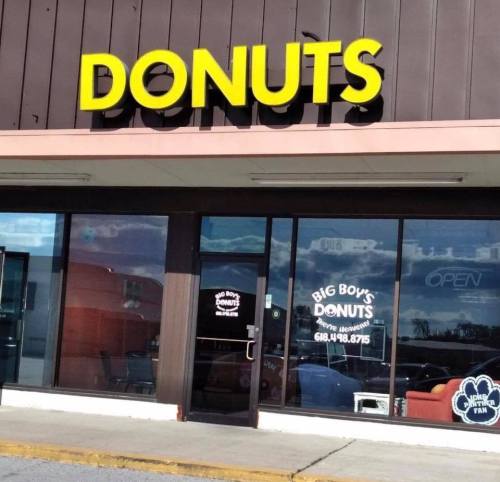 A storefront with a large "DONUTS" sign and "Big Boy's Donuts" in the window, featuring a cozy seating area inside.