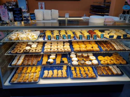 A display case filled with a variety of donuts and pastries, showcasing different shapes and toppings.