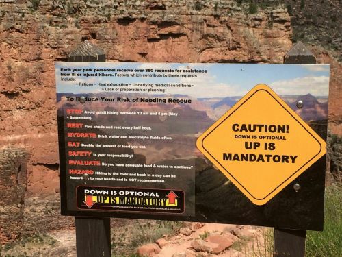 Sign with safety tips for hikers in a canyon, warning about risks and emphasizing that "Up is Mandatory."