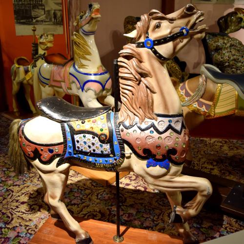 A vintage carousel horse with ornate decorations and vibrant colors, set against a colorful background.