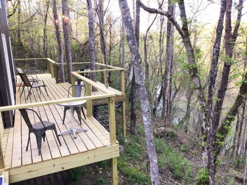 A wooden deck surrounded by trees, overlooking a serene river in a natural setting.