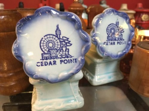 Two decorative souvenirs featuring a blue and white design with "CEDAR POINT" and an amusement park scene.
