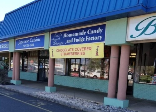 Storefront featuring signs for Japanese cuisine, homemade candy, and chocolate-covered strawberries.