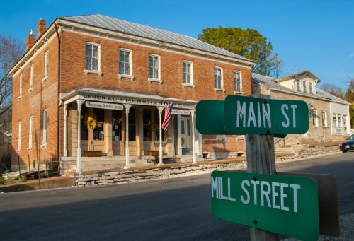 Historic brick building at the corner of Main Street and Mill Street, featuring an American flag and a quaint storefront.