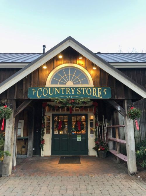 A charming country store entrance adorned with holiday decorations and warm lights.
