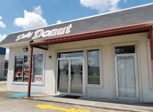 Exterior of Daily Donut shop with a large "OPEN" sign and a clear blue sky in the background.