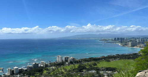 Wide coastal view of Honolulu and turquoise waters from the summit overlook of the Diamond Head hike.