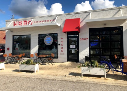 Exterior of Hero Doughnuts & Buns, featuring a red awning, outdoor seating, and a bright storefront.
