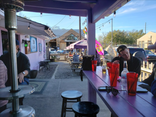 Outdoor seating area of a vibrant café with colorful decorations and patrons enjoying the sunny day.