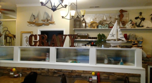 A cozy restaurant interior featuring a decorative counter with the word "GRAVY" and nautical-themed decor.