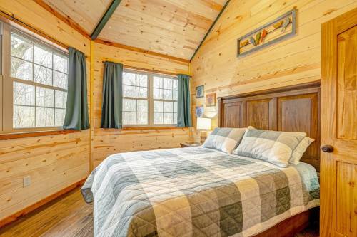 Cozy bedroom with wooden walls, a quilted bedspread, and large windows letting in natural light.