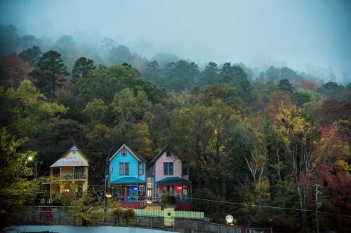 Colorful houses nestled among misty trees in a serene, autumn landscape.